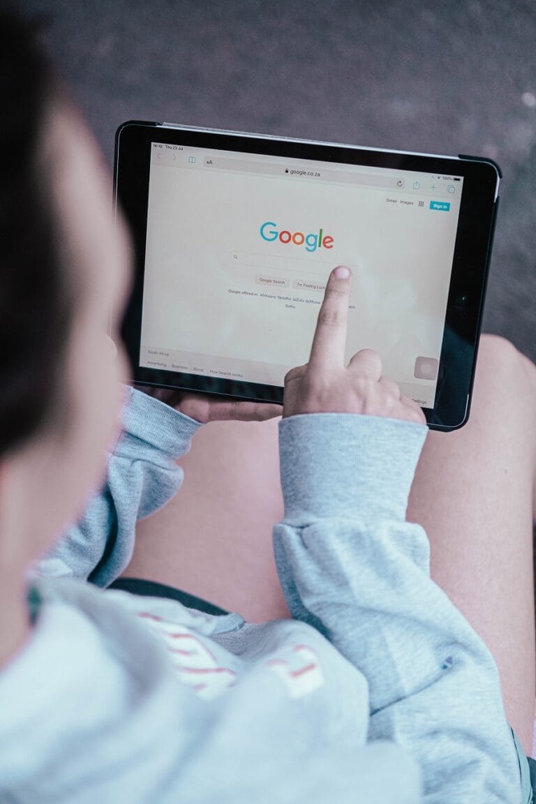 Man holding a tablet and searching on Google, representing online research and digital behavior